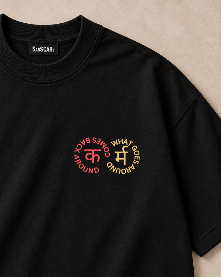 Karma black oversized tee laid flat, close-up of the कर्म circle print